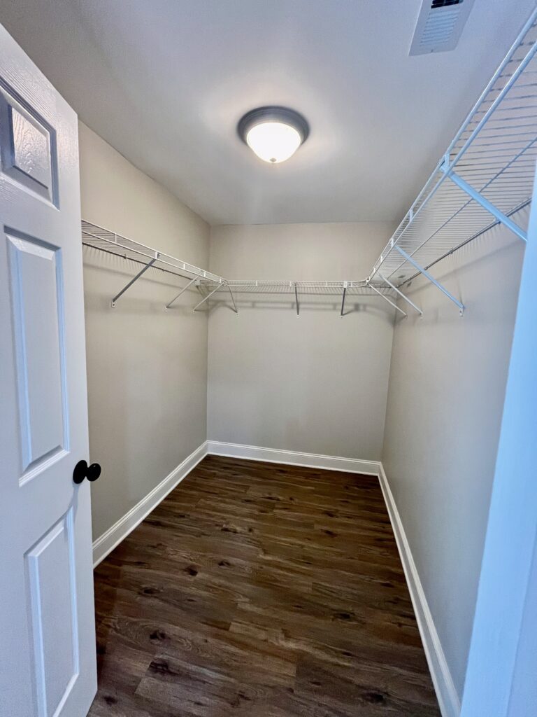 walk-in closet with built-in white wire shelving and wooden floor