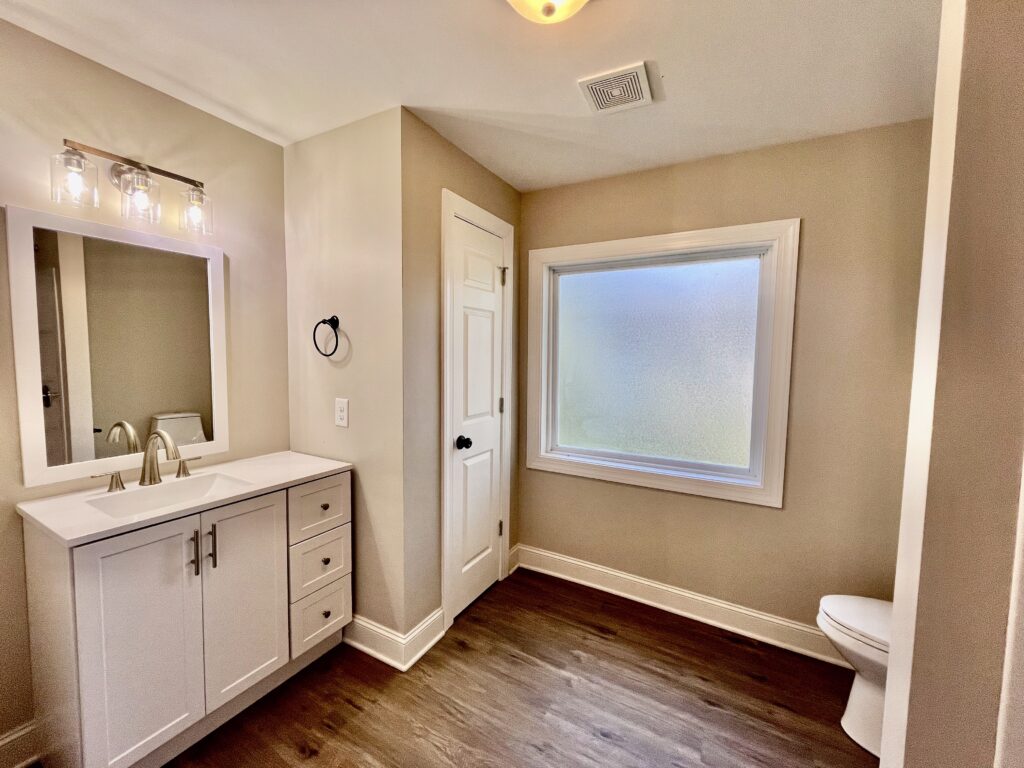 toilet with kamod and sink with mirror and large window
