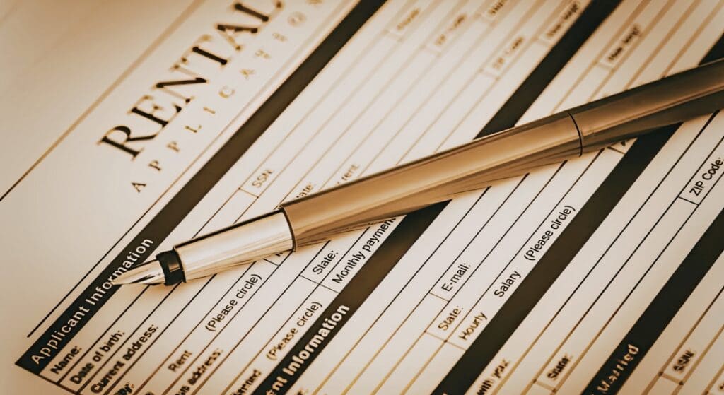A pen rests on top of a rental application form, partially filled out with applicant information sections visible.
